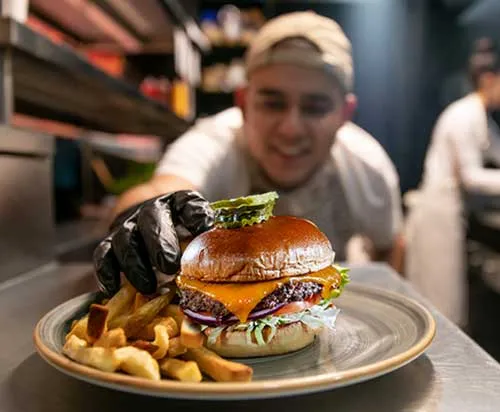 A server with a burger and fries on a plate