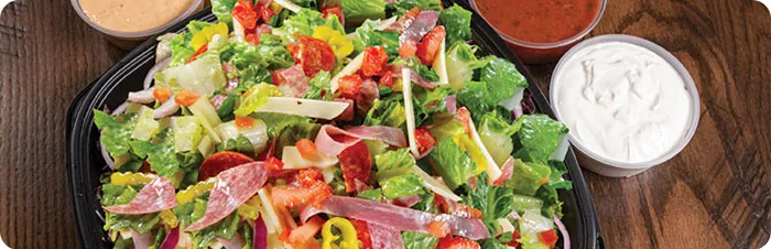 Beef's 1985 Salad in a large serving dish surrounded by dressings