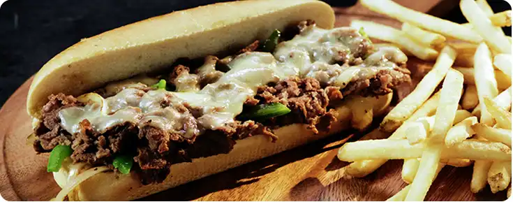 A philly cheesesteak sandwhich with fries
